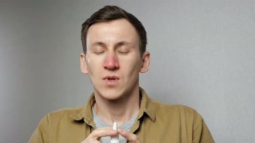 Un homme pulvérise un médicament nasal dans les narines pour obtenir un soulagement
