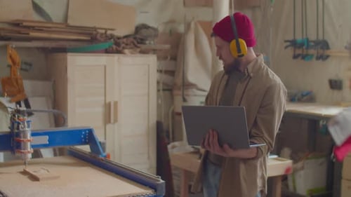 Carpenter Operating Woodworking CNC Machine with Laptop