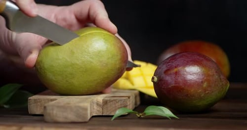 Hands Cutting Mango on Wood Cutting Board