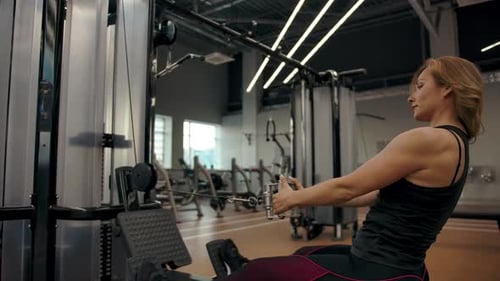 Woman Exercising Using Seated Cable Row Machine in Gym