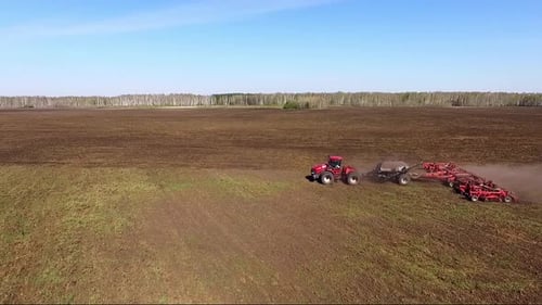 Aerial view of Tractor plow in a huge field. Summer, sunny day.
