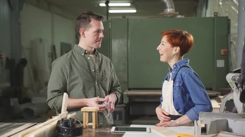 Two Carpenters Working As Wood Designers in Small Carpentry Workshop