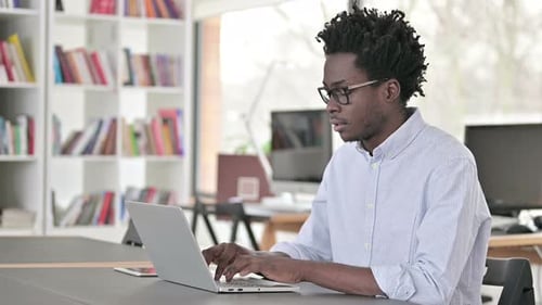 Young Adult Types on Laptop in Office Setting