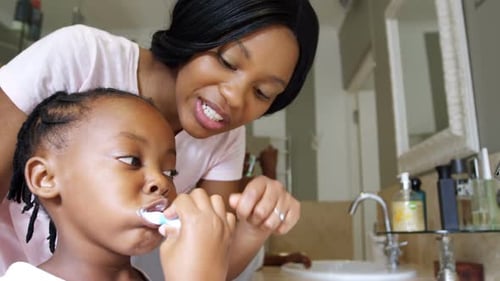 Mother Watches Child Brush Teeth in Bathroom