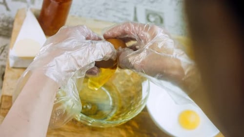 Gloved Hands Cracking Eggs for Cooking Preparation