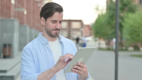 Young Adult Man Uses Tablet in Urban Setting