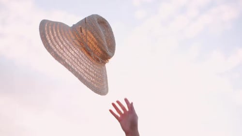 Woman Tosses Straw Hat in Summer Field