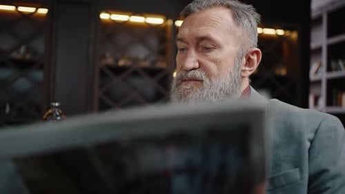 Zoom Out Portrait of Serene Senior Bearded Businessman Reading Newspaper at Bar Relaxing Alone in