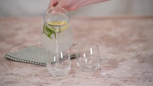 Pouring Refreshing Lemonade into Two Glasses