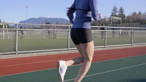 Woman Running on an Outdoor Track on Sunny Day