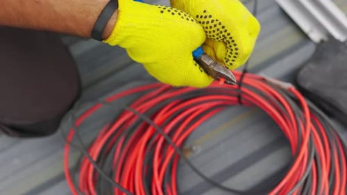 Hands Cutting Electric Wire with Pliers