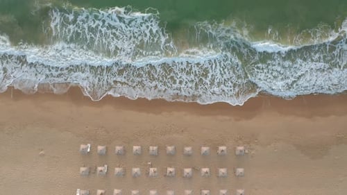 Sandy beach with straw sunshades and sunbeds