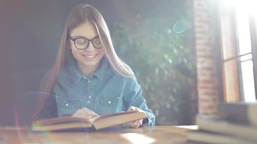 Woman Reads Book at Table in Bright Light