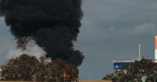 Unfall in der Ölraffinerie - riesige Explosionen und Feuerbälle steigen auf. Dicker schwarzer Rauch bedeckt den Himmel.