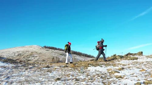 Hikers Trekking Across Snowy Mountain on Sunny Day