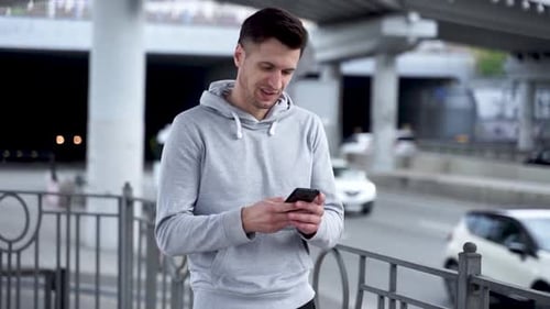 Man Using Phone on Urban Street