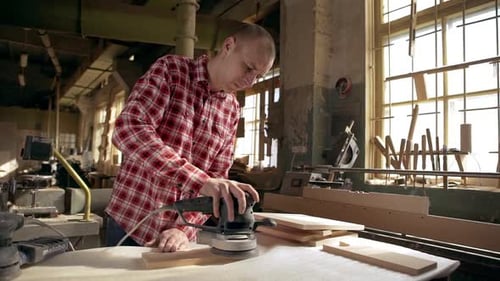 Man Sands Wood in Workshop with Power Tool