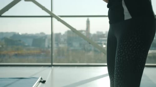 Tiltup of Slender Young Woman in Sportswear Taking Bottle and Drinking Water in Gym