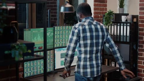 Man Analyzes Stock Data on Multiple Screens