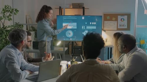 Motivated Employee Explaining Business Ideas to Diverse Group of Colleagues in Dark Office at Night