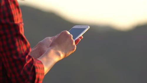 Person Using Mobile Phone at Sunset in Nature