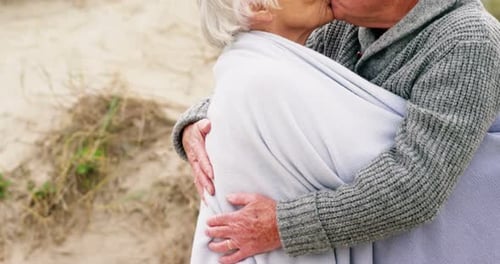 Senior Couple Shares Affectionate Kiss on Beach