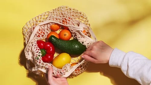 Hands Taking Fruit and Vegetables from String Bag