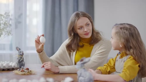 Woman and Child Decorate Easter Eggs at Table