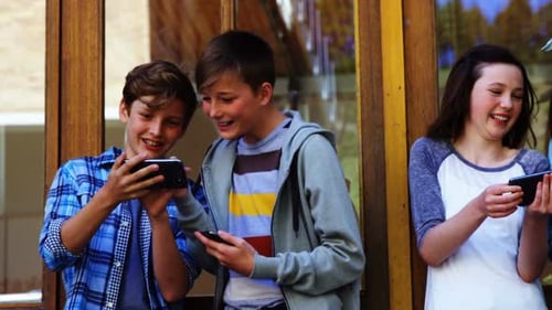 Group of school friends using mobile phone outside school