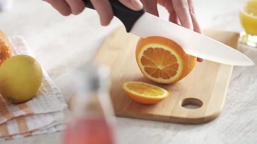 Slicing fresh orange on cutting board at home