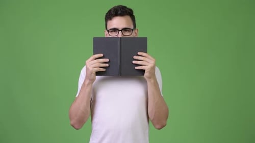 Young Man Lowering Book With a Green Screen Background