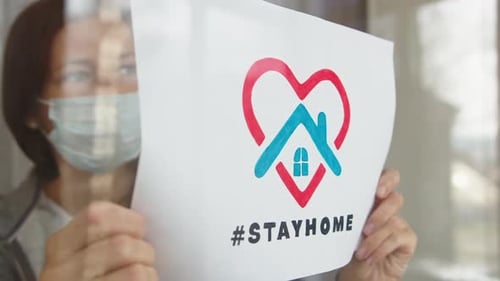 Woman in Mask Holds Stay Home Sign