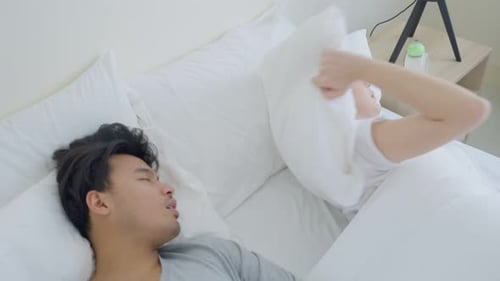 Une femme asiatique frustrée par son mari ronfle après son réveil sur son lit dans la chambre.