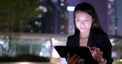 Adult Woman Uses Tablet in City at Night
