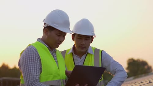 Zwei Ingenieure überprüfen die Effizienz des Solarmoduls und verwenden einen Laptop