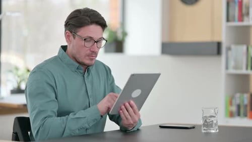 Man Using Tablet at Table Indoors