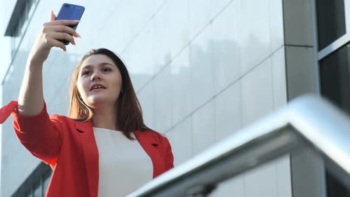 Business Woman in a Red Jacket Makes Selfie on the Street