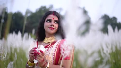 Une femme mariée indienne romantique et attentionnée détourne le regard en tenant une conque ou un shankha dans un champ