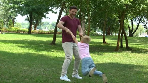 Vater und Sohn spielen im Park, zeigen Daumen hoch, schätzen die Zeit mit der Familie
