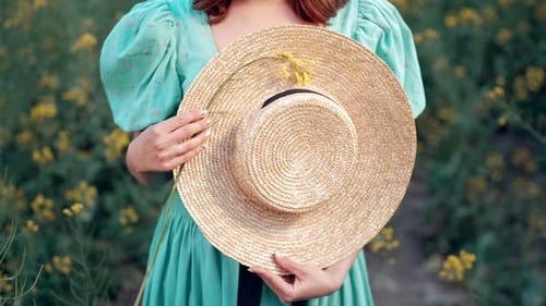 Woman Holding a Straw Hat in Flower Field