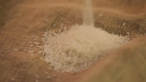 Viele Reissamen auf braunem Sackleinen gießen, Bio-Lebensmittel für gesunde Ernährung