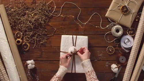 Hands Tying Ribbon on Christmas Present Overhead Shot
