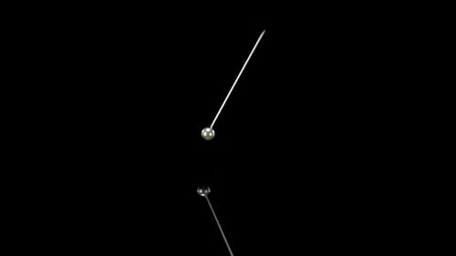 Swinging Silver Ball Pendulum on Black Background