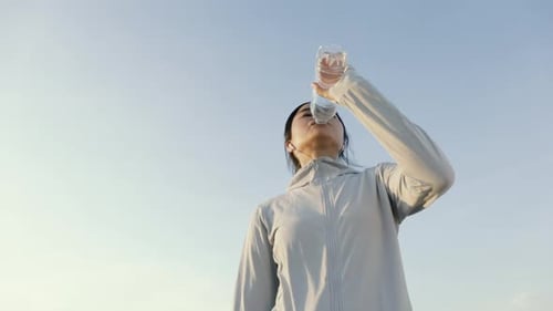 Woman Drinking Water During Outdoor Workout in Sunlight