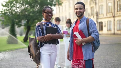 Young Happy Couple of Students Looking at Camera Smiling Standing on Sunny University Yard with
