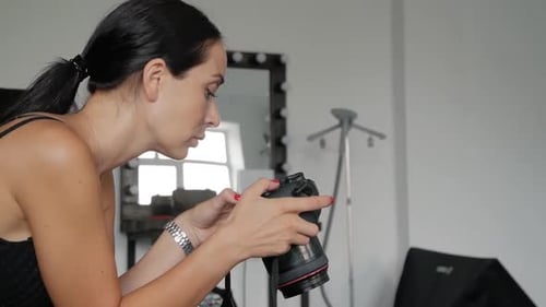 Woman Photographer Inspecting Camera in Studio Setting