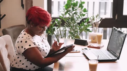 Serious Young African Businesswoman Using Tablet at Cafe