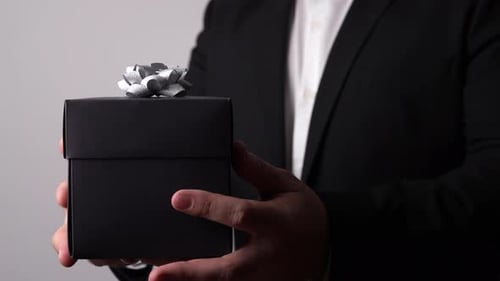 Man in Suit Presents Elegant Gift Box