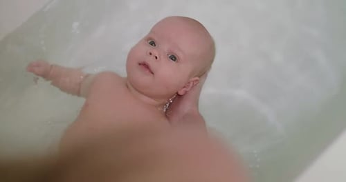Adorable Infant Enjoying a Bath with Support