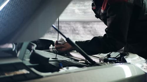 Mechanic Checks Car Engine Oil Level in Garage